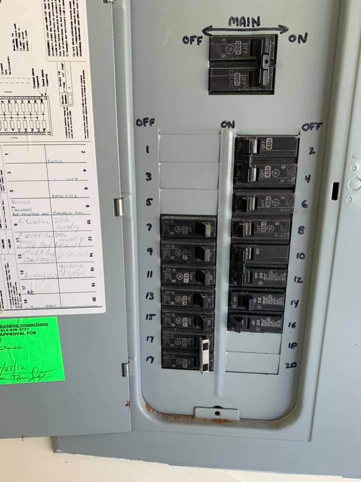 An industrial electrician in Erie, PA installs and maintains a circuit breaker box with multiple circuits.