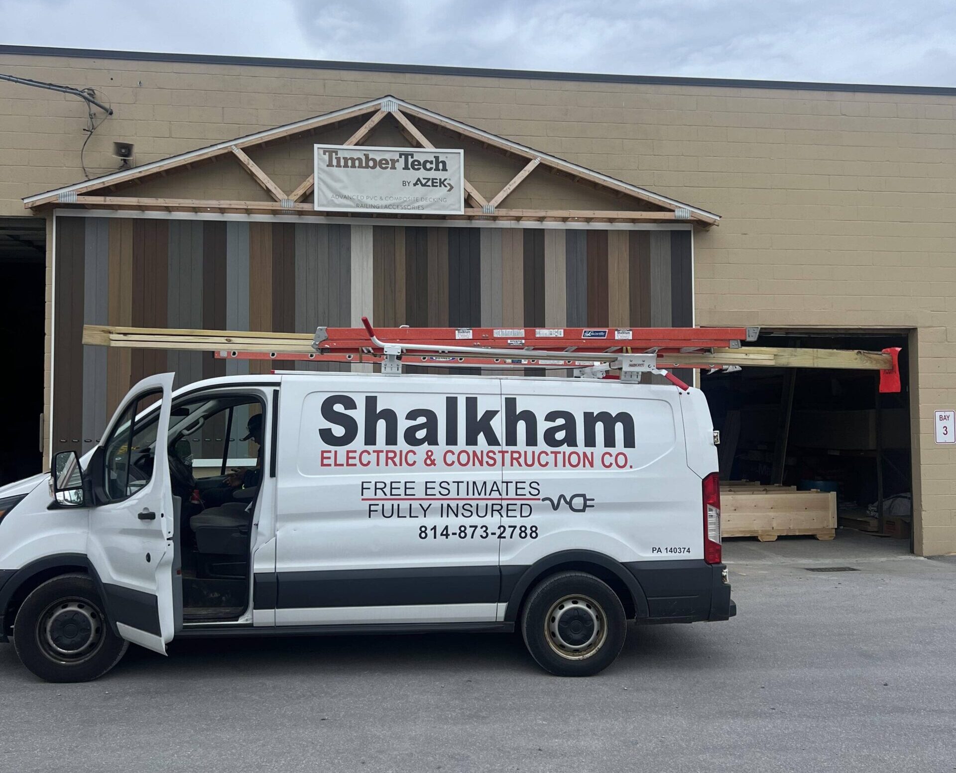 A van parked in front of a building that says Shalham Electrical, an electrical contractor in Erie, PA.