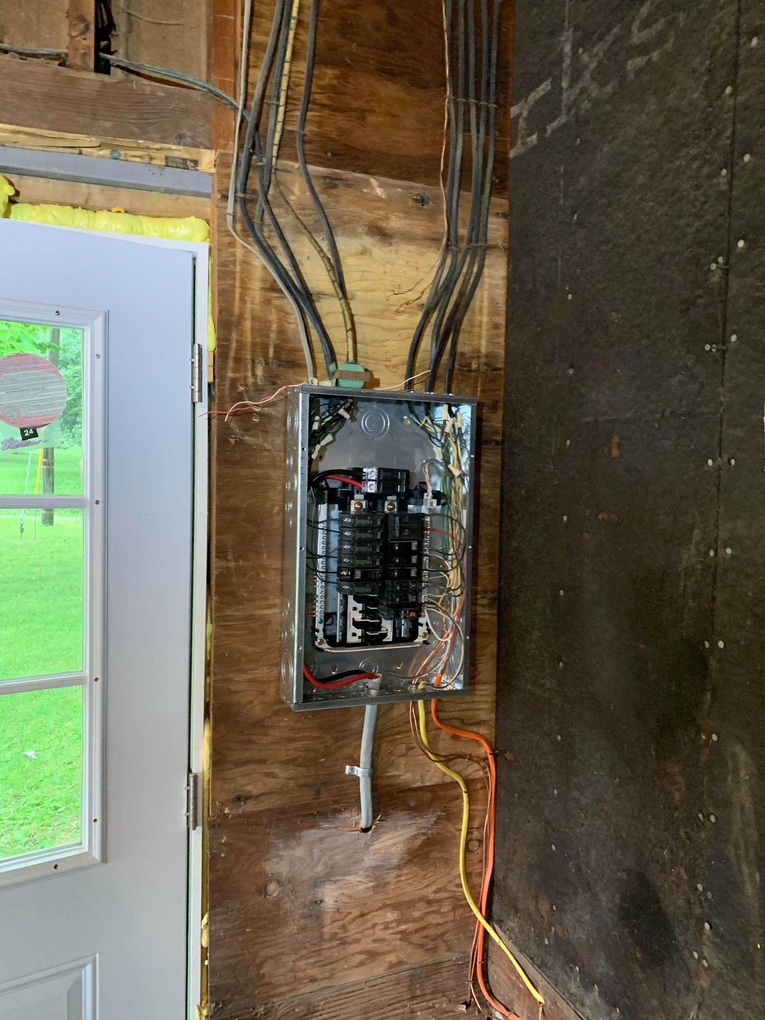 A professional electrician in Erie, PA installs an electrical panel in a house.