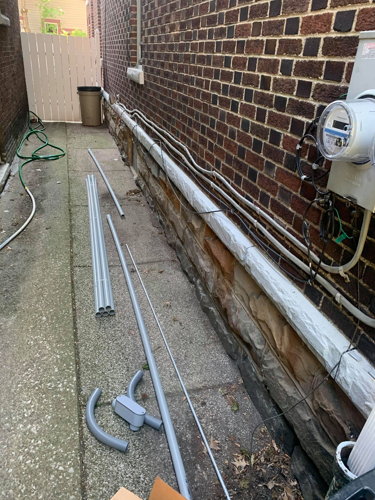 A residential electrician in Erie, PA, is seen working on a sidewalk next to a brick wall.