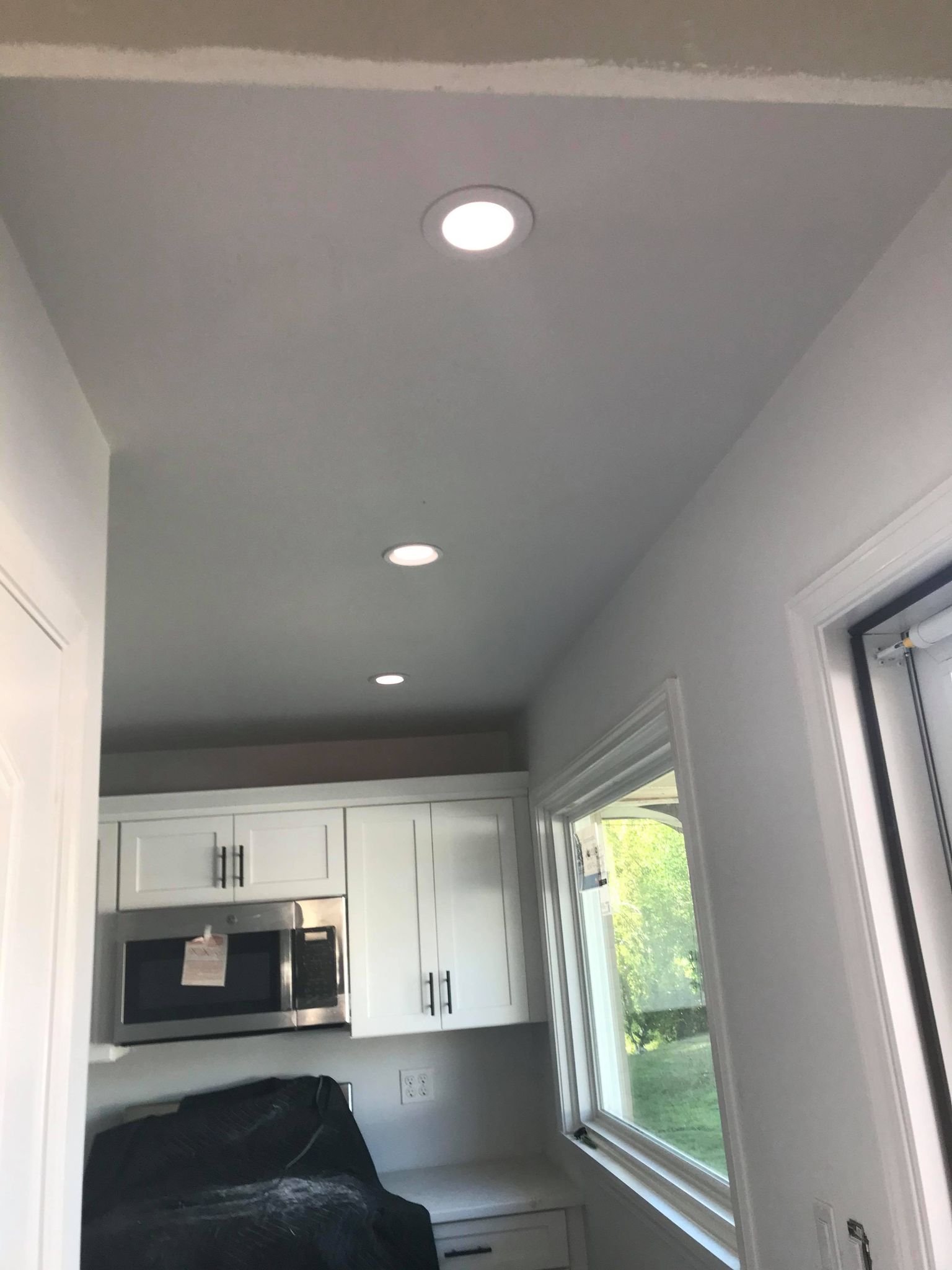 A kitchen with white cabinets and a white ceiling, seeking the services of an expert residential electrician in Erie, PA.