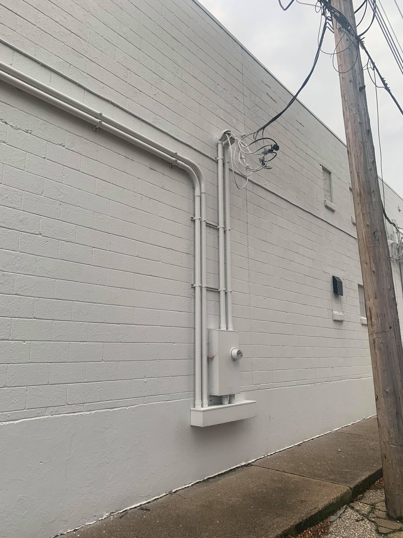 A white building with pipes on the side of it, featuring industrial electrical contractors in Erie, PA.