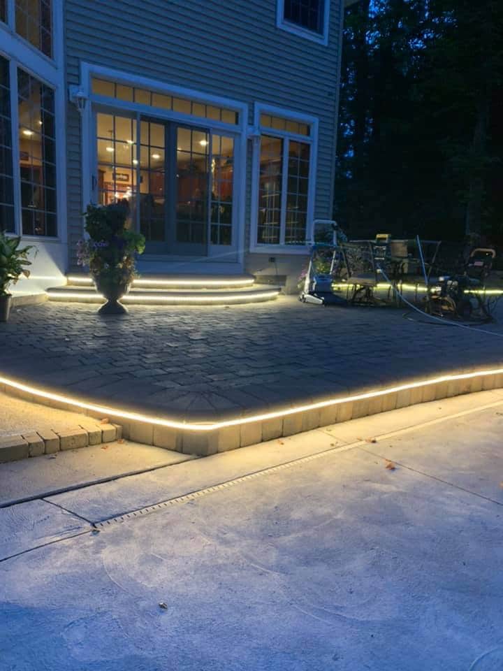 A patio with a walkway illuminated at night by an expert electrician in Erie, PA.